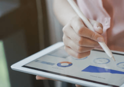 a hand holding a pen to type on a tablet showing graphics